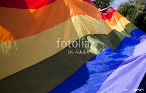 Person Holding Rainbow Logo - people holding giant rainbow flag at pride parade - LGBT symbol ...