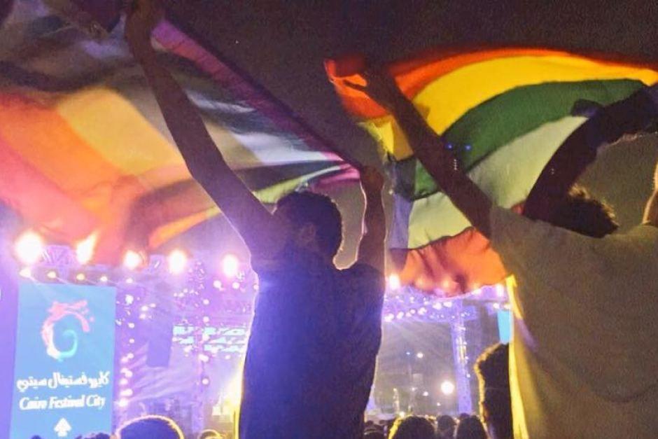 Person Holding Rainbow Logo - Image of two people holding up a rainbow flag at a concert in Cairo ...