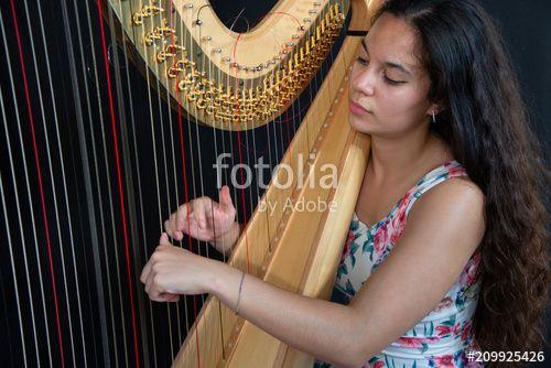 Woman Harp Logo - Close-up of a beautiful girl with long brown hair playing the harp ...