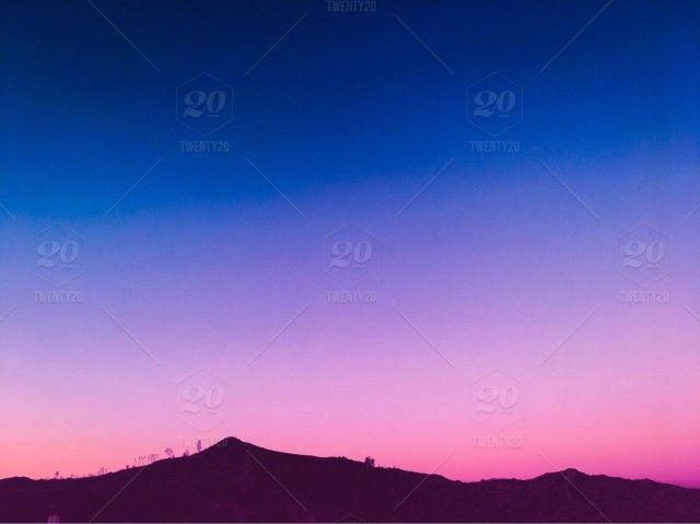 Pink and Blue Mountain Logo - Silhouette of mountaintop against a vibrant pink and blue sunset sky ...