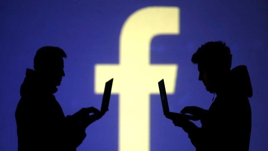 I Can Use Facebook Logo - Two men use laptops against a backdrop of Facebook logo