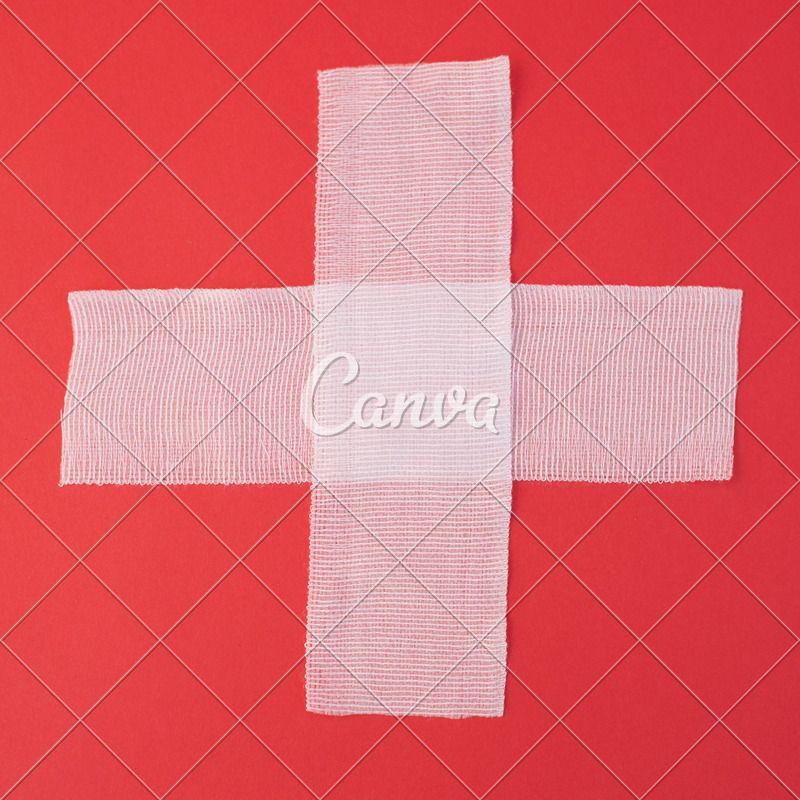 Cross Red Background Logo - Two sheets of gauze forming cross on red background, overhead view