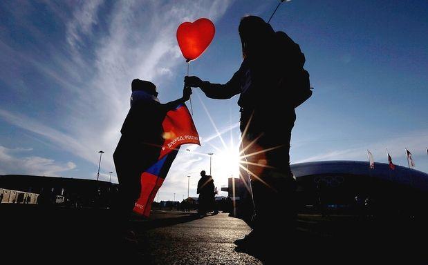 Heart Shaped Olympic Logo - An Olympic volunteer, right, hands a heart-shaped balloon to a child ...