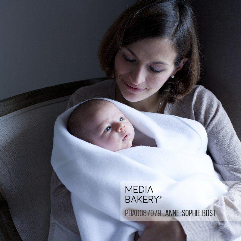 Woman Holding Baby Blue Logo - Mediabakery - Photo by PhotoAlto Images - Woman holding newborn baby